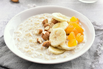 Oatmeal porridge with banana slices, nuts and dried apricot