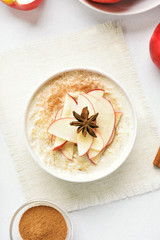 Fototapeta na wymiar Oatmeal porridge with red apple slices and cinnamon