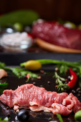 Flat lay of raw beefsteak with vegetables, herbs and spicies on metal tray, close-up, selective focus