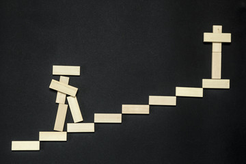 A creative wooden man climbs the stairs, at the end of it there is a cross. The concept of life and...