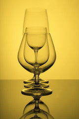 Glass glasses stand in a row on a yellow background.