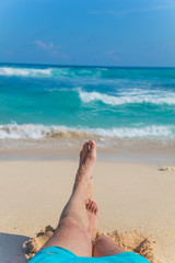 Man lying and enjoying on a sandy tropical beach.