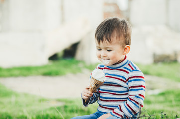 little cute boy eating ice cream three years very appetizing, amid nature, green grass