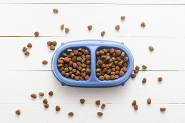 Pet food for dog or cat in bowl on wooden background top view flat lay