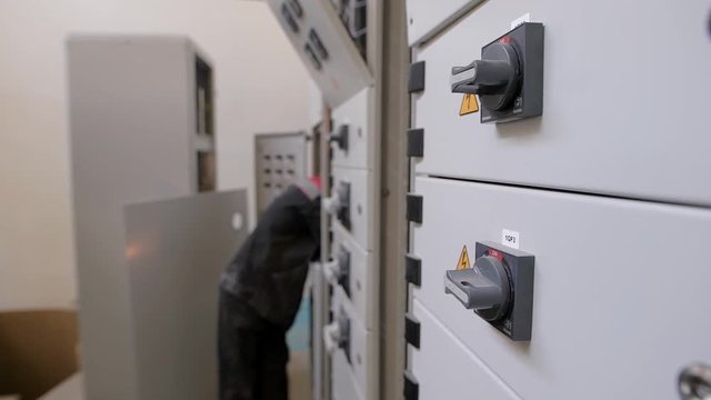 Side view of unrecognizable technician working and repairing electric box