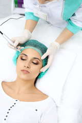 Naklejka premium Professional beautician doing eyebrow tattoo at woman face. Permanent brow makeup in beauty salon, closeup. Cosmetology treatment