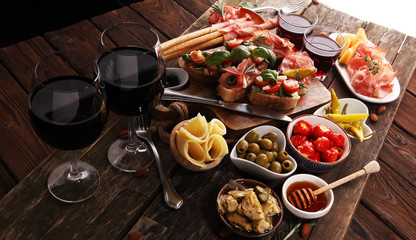 Italian antipasti wine snacks set. Cheese variety, Mediterranean olives, pickles, Prosciutto di Parma, tomatoes, artichokes and wine in glasses