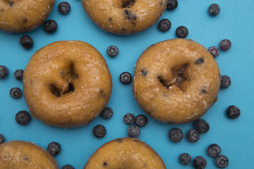 Blueberry Donuts with Scattered Blueberries on a Blue Background