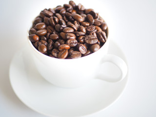 a white cup filled with brown coffee beans.