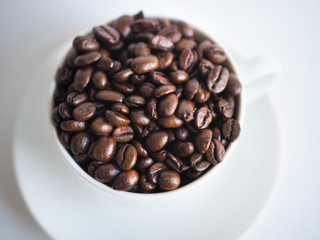 a white cup filled with brown coffee beans.