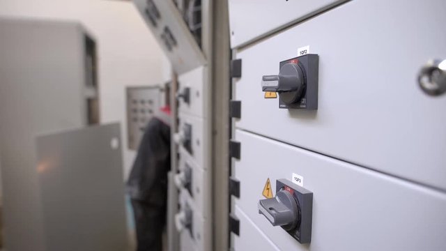 Side view of unrecognizable electrician inspecting and working with box indoors
