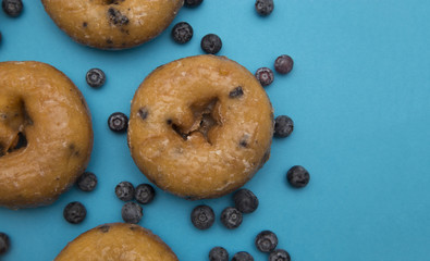 Blueberry Donuts with Scattered Blueberries on a Blue Background