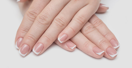 Fototapeta premium Manicure with rhinestones in the shape of hearts and pink balls on white and red nail Polish on a white background.