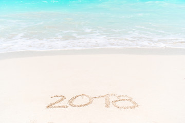 2018 handwritten on sandy beach with soft ocean wave on background