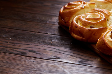 Homemade rose buns on wooden cutting board over rustic vintage background, close-up, shallow depth of field