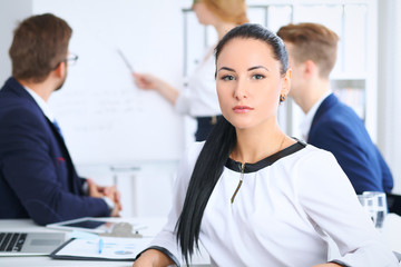 Fototapeta premium Business People at meeting in office. Focus at beautiful cheerful smiling woman. Conference, corporate training or brainstorming of people group. Success and negotiation concept