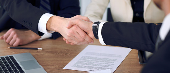 Close up of business people shaking hands at meeting or negotiation in the office. Partners are satisfied because signing contract