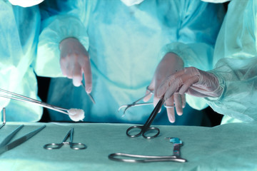 Group of surgeons in masks performing operation. Scene of operation room colored in green. Medicine, surgery and emergency help concepts