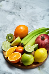 Ripe fresh fruits in a wooden plate on a light wooden background, selective focus, close-up, top view