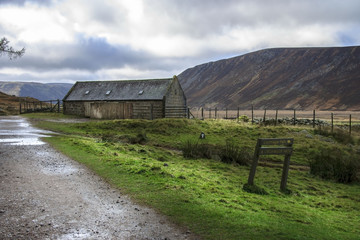 Cottage in Cairngorms National Park and Royal Deeside at Loch Muick, Ballater, Aberdeenshire, Scotland and sign with description paths to Lochnagar and Loch Muick.