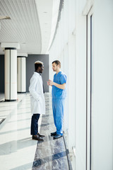 Fototapeta premium Medical mixed race staff having Discussion In Modern Hospital Corridor