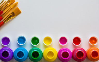 Colorful paint bottels and paint brushes on white background with copy space, top view/arts and crafts background concept