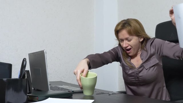 A young woman poured tea onto a laptop. works in the office. Slow-motion shooting, 4k