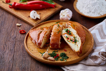 Delicious rustic pastries filled with herbs and vegetables on a wooden plate over a vintage background, selective focus