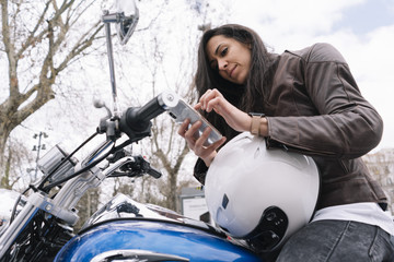 Woman with a motorcycle in the city using the smartphone
