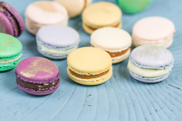 Obraz na płótnie Canvas Close-up colorful French or Italian macaron on blue wooden table. Macarons is French dessert served with tea or coffee. wallpaper, Horizontal photo