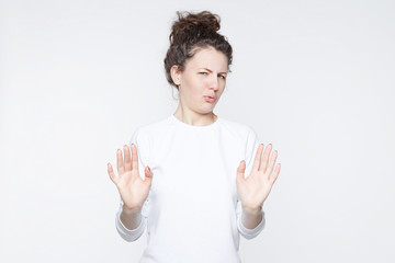 Body language. Disgusted stressed out beautiful young woman with hair knot posing at studio wall,...