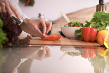 Close Up of human hands cooking vegetable salad in kitchen on the glass table with reflection. Healthy meal, and vegetarian food concept