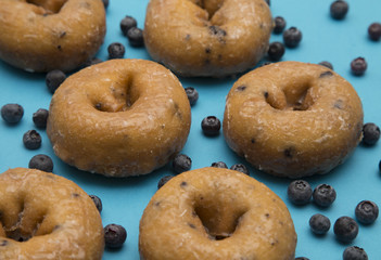 Blueberry Donuts with Scattered Blueberries on a Blue Background