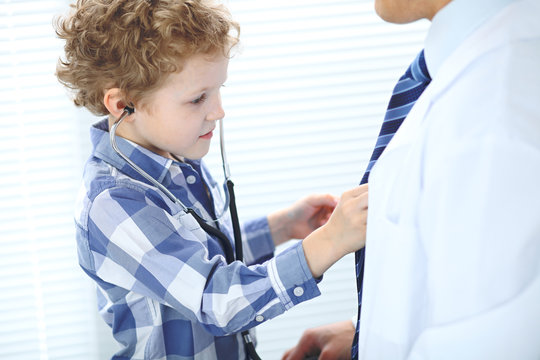 Doctor and child patient. Little boy play with stethoscope while physician communicate with him. hildren's therapy and trusting relationship in medicine concept