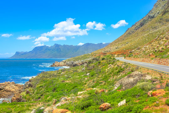Scenic coastal Route 44 or Clarence Drive on False Bay near Cape Town between Gordon's Bay and Pringle Bay in Western Cape, South Africa. Hottentots Holland Mountain range on background. Summer season