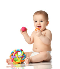 Infant child baby boy toddler sitting in diaper playing with balls and plastic toys isolated 