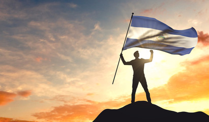 Nicaragua flag being waved by a man celebrating success at the top of a mountain. 3D Rendering - obrazy, fototapety, plakaty