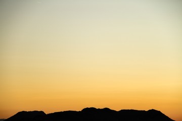 A silhouette of a desert mountain with the sky providing copy space.