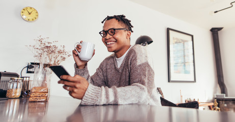 African man using phone and drinking coffee