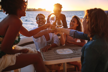 Group of friends having drinks at sunset boat party