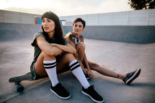 Female friends sitting relaxed at skate park