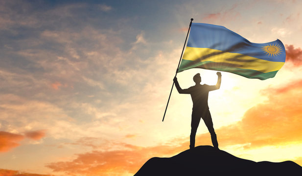 Rwanda flag being waved by a man celebrating success at the top of a mountain. 3D Rendering