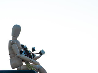 Wooden mannequin with a bouquet of closed flowers in his arms on springtime Solitude and Love concept