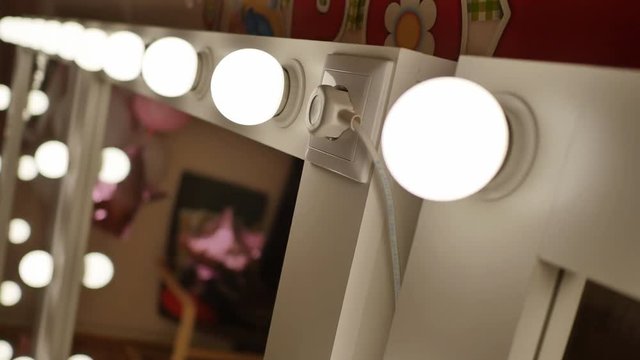 Four make-up mirrors stand in the room and are lit. Video shooting in motion.