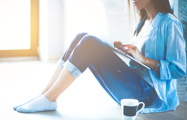 Young beautiful woman at home sitting on the floor with laptop. Young beautiful woman.