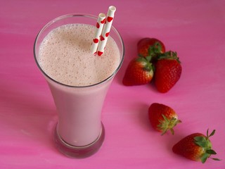 Batido de fresas sobre fondo rosa con alto contraste de color
