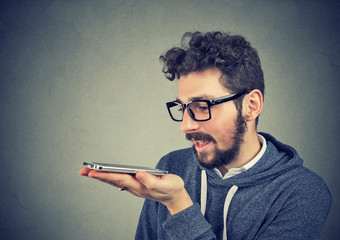 Naklejka premium Hipster man in glasses using a smart phone voice recognition function