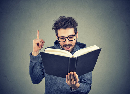 Excited hipster guy reading a book
