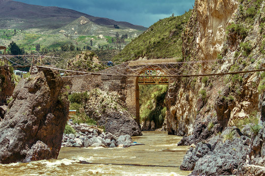 Suspension bridge and stone bridge over rapids of the Colca River in Peru