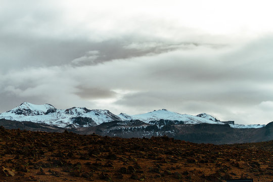 Snowy summits at sunrise with apachetas in front of a route in Arequipa, Peru
